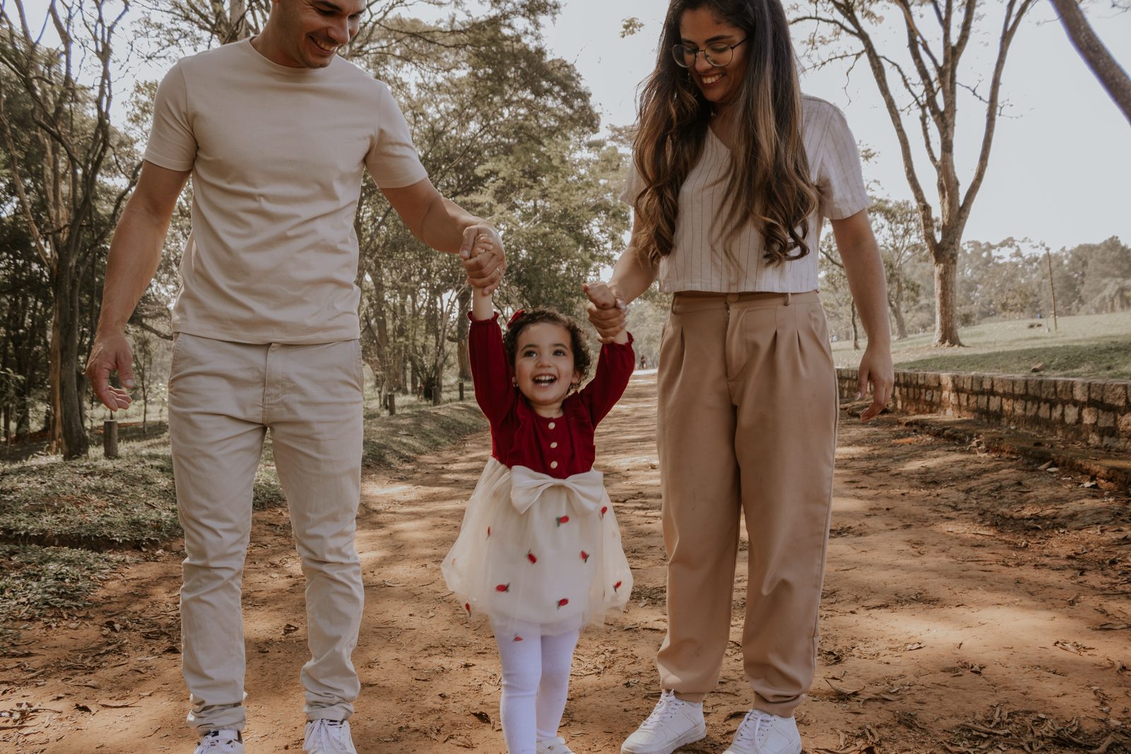 Criança de mãos dadas com o pai e a mãe
